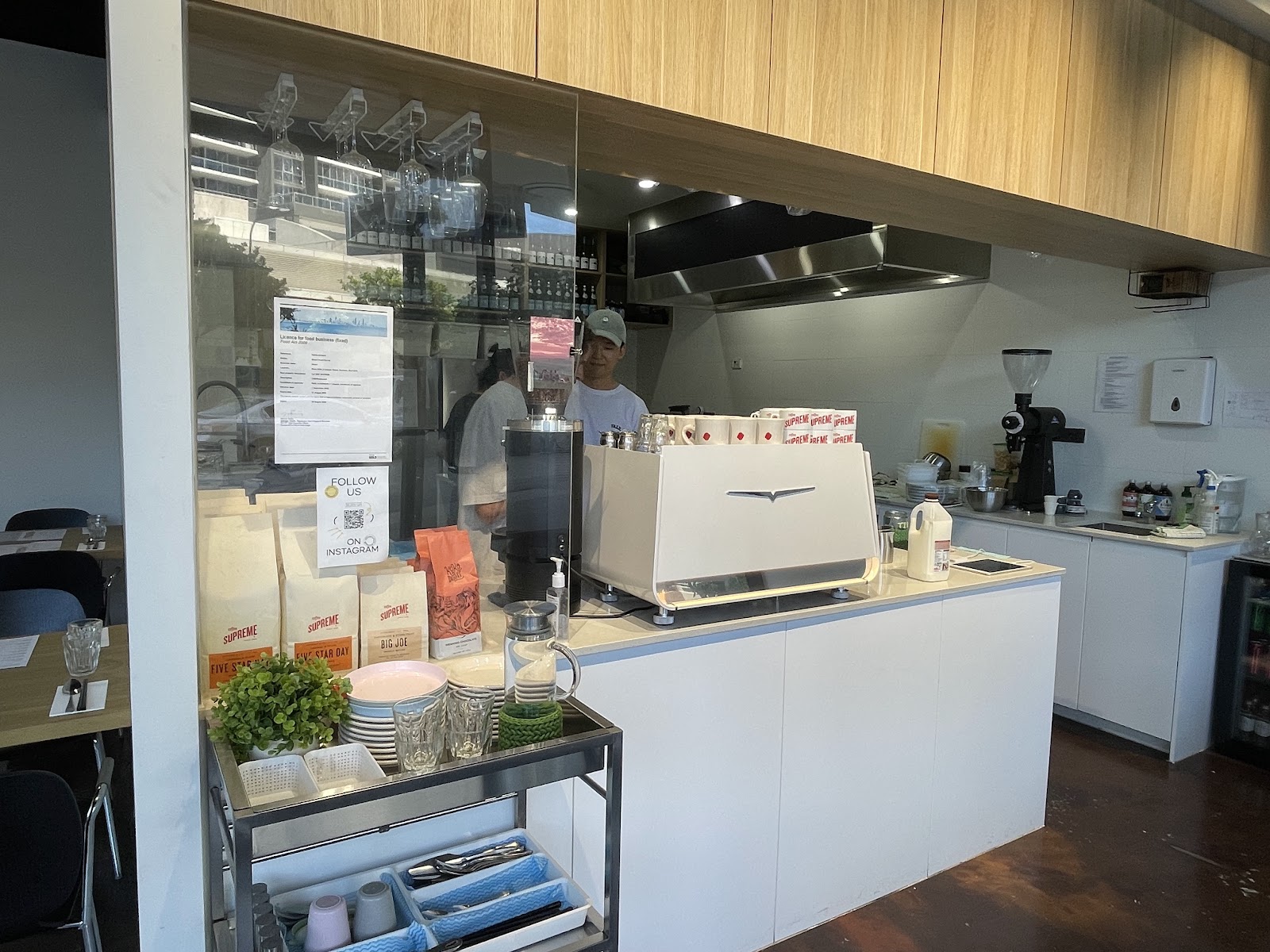 The counter at Minari with its white espresso machine, bags of coffee beans and the kitchen behind