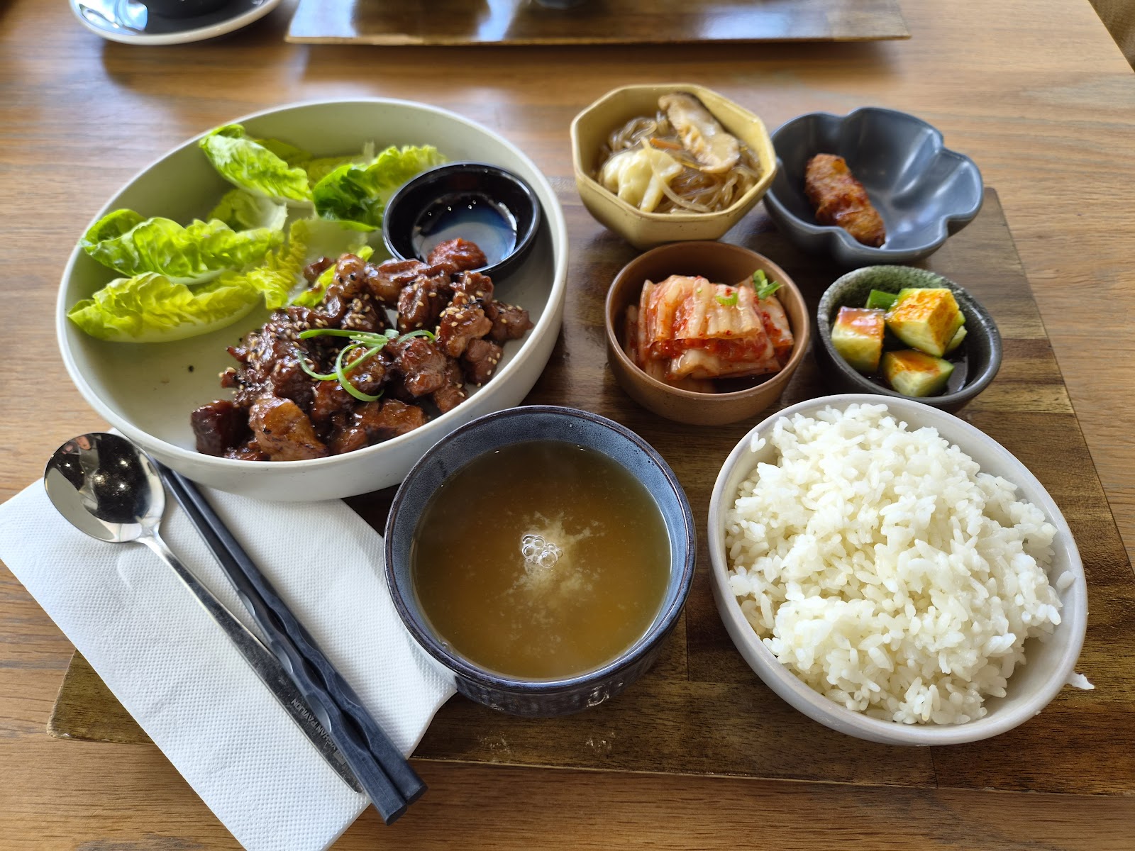 A soban set at Minari: glazed galbi with lettuce, kimchi, japchae, soup and rice on a timber board